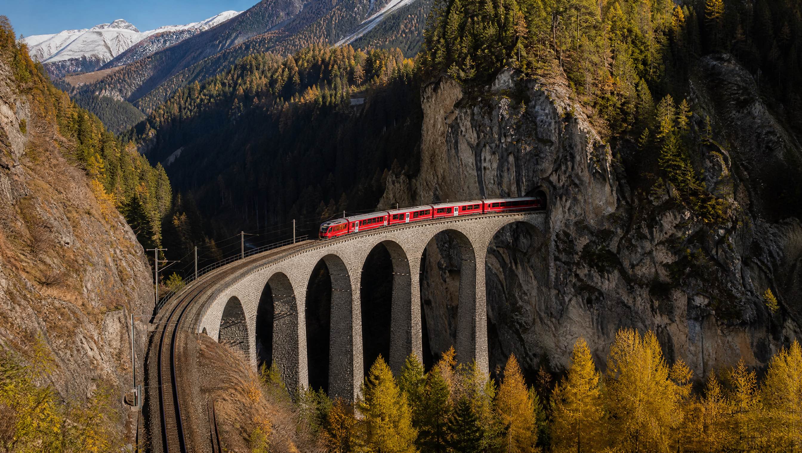 A red Rhaetian Railway train crossing the Landwasser Viaduct in Switzerland