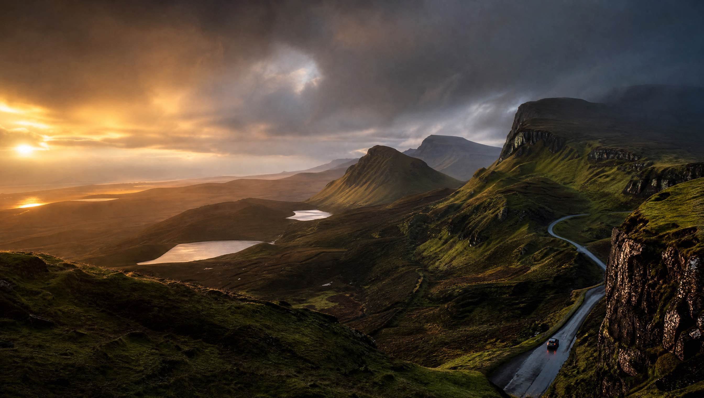 A winding road beneath the dark ridges of the Isle of Skye